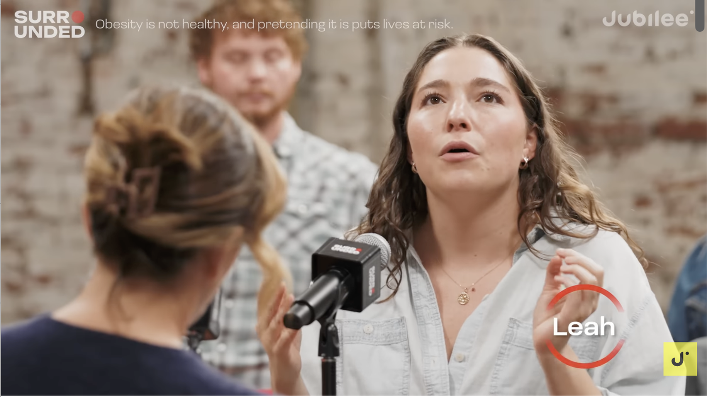Participant named Leah speaking into a microphone during the Jubilee Surrounded debate